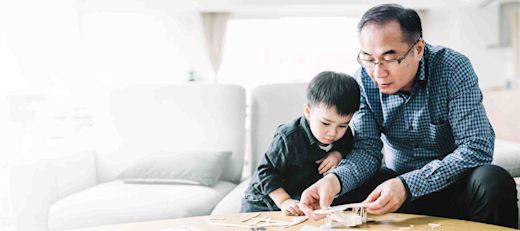 Grandfather assembling model airplane for cute grandson.