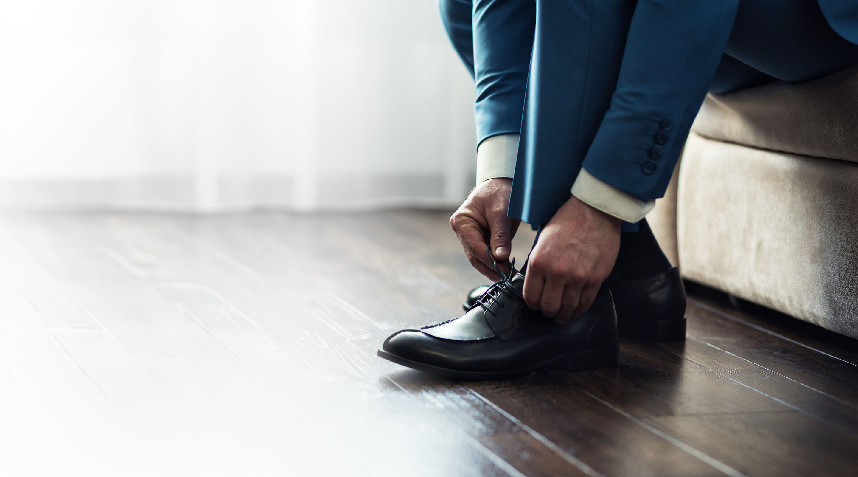 A man ties the laces on his loafers