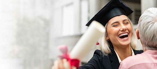 A female graduate in a cap and gown hugs her grandparent.