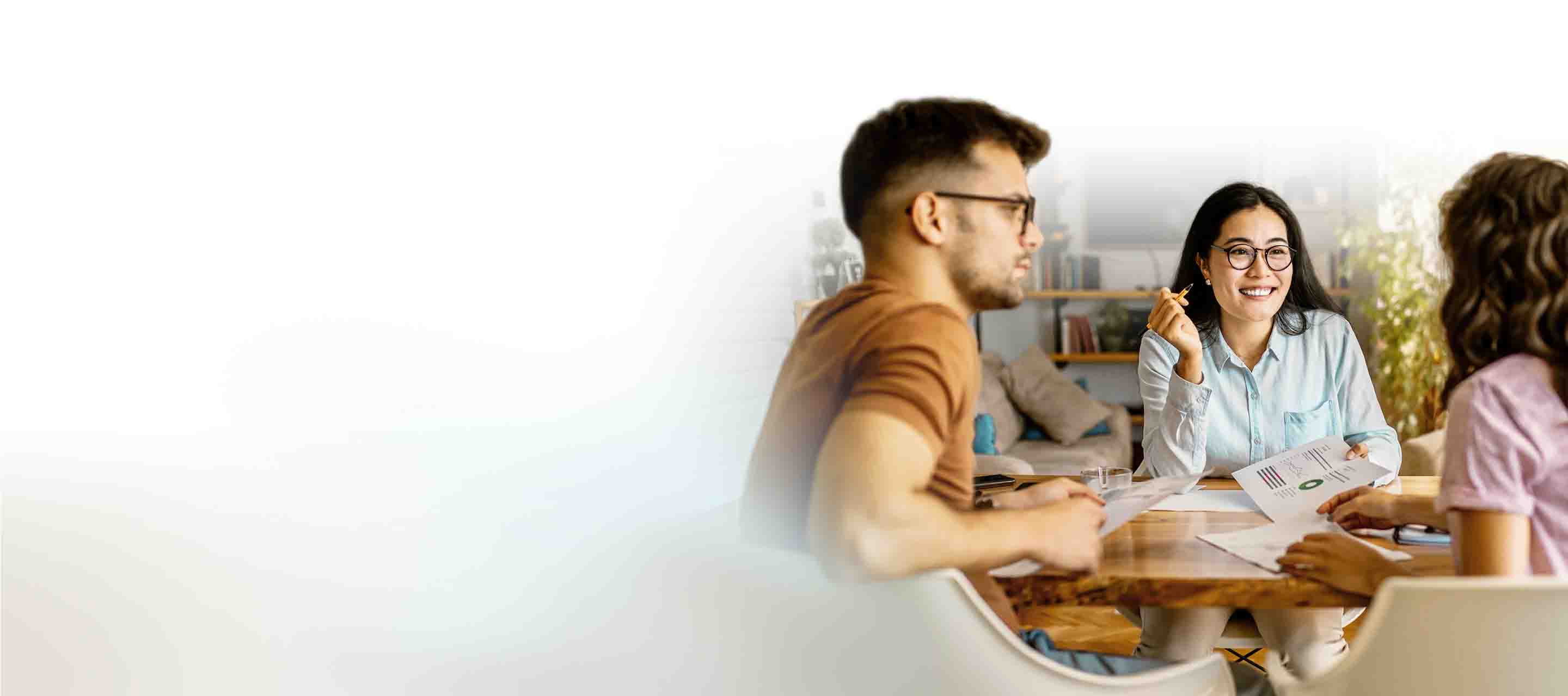 A couple engaged in conversation with a Sales Representative, seated at a table and displaying connection with each other. 