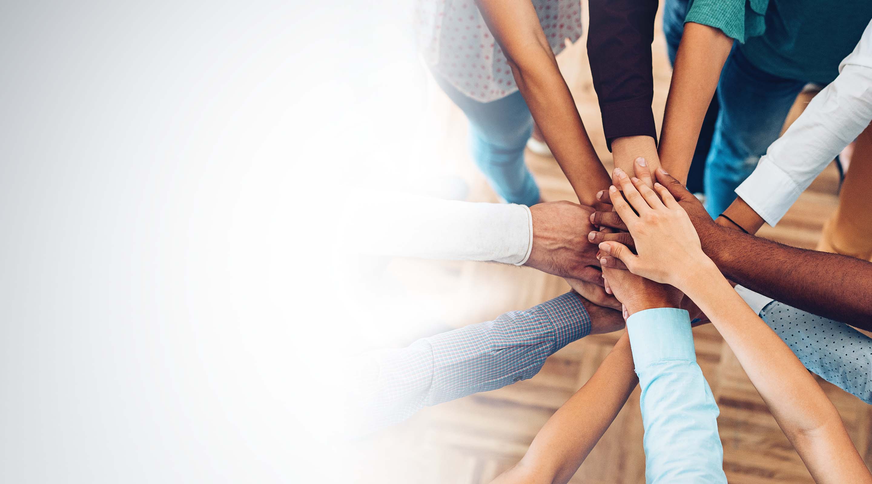 A group of mixed races puts their hands together in a show of unity