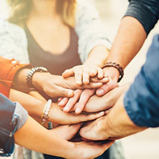 A close up picture of hands stacked on one another as if the group is about to say, "go team!"