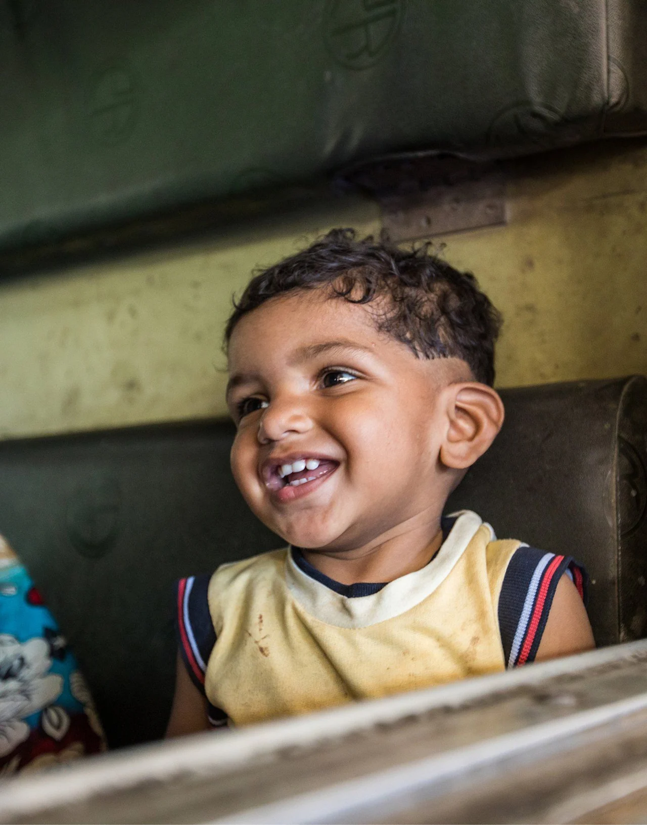 A smiling child in a yellow jersey