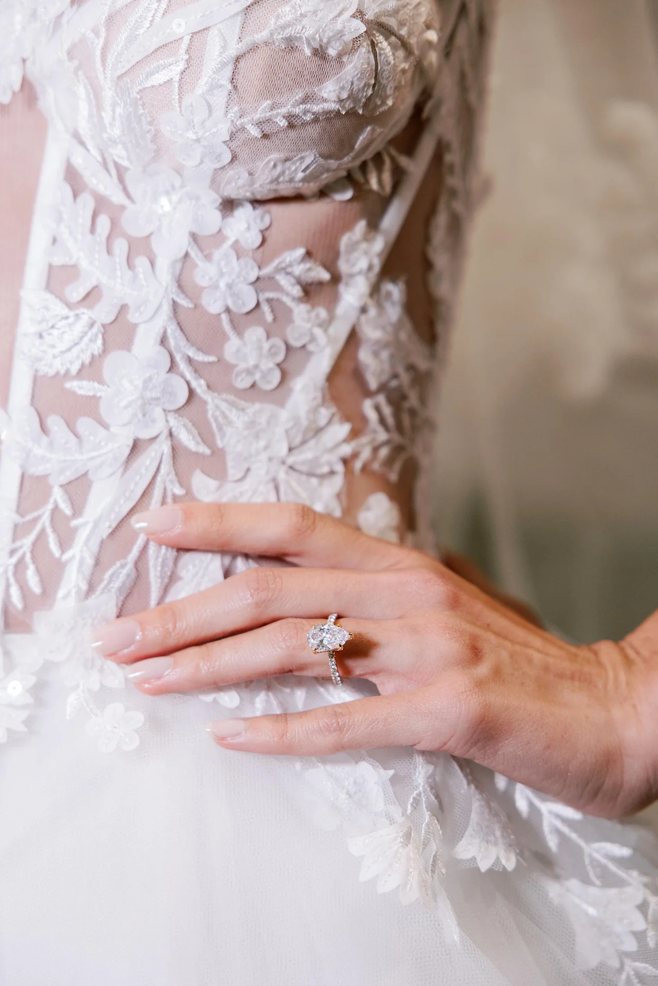 A bride's hand resting on embroidered lace
