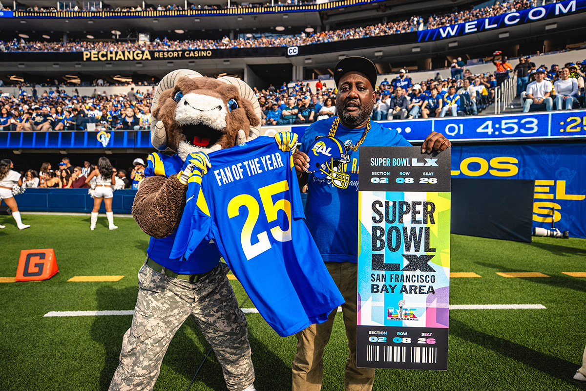 Rams Mascot holding jersey with fan holding oversized ticket