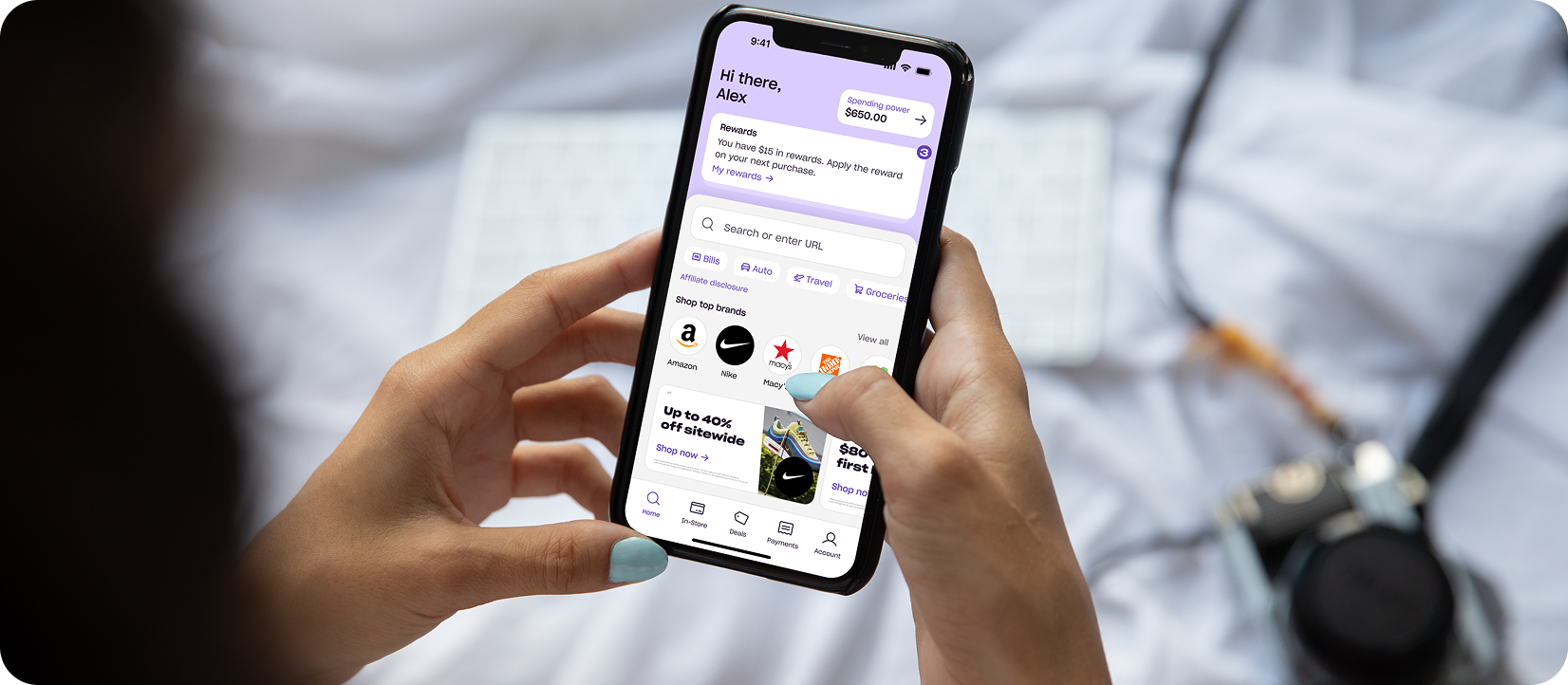 Person holds a smartphone showing the Zip app home screen with spending power, rewards, and top brands to shop