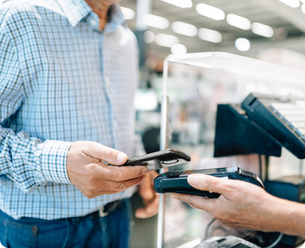 Shopper using a mobile phone to make a contactless payment at a retail checkout