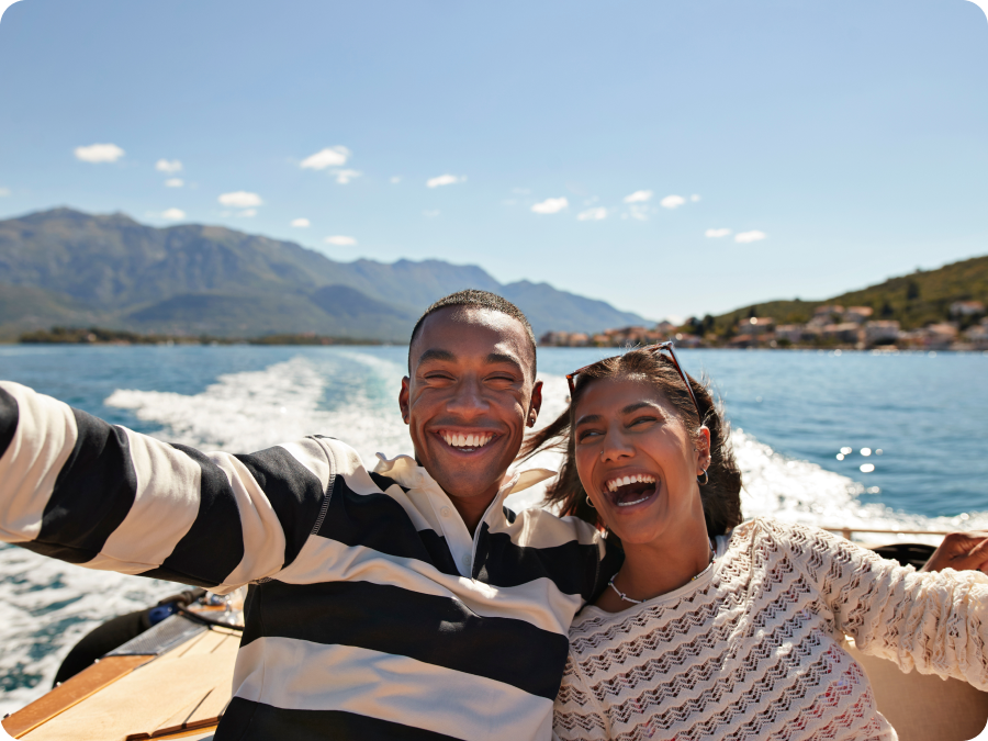 Couple laughing on a boat trip with mountains behind them, illustrating travel booked with Zip buy now, pay later