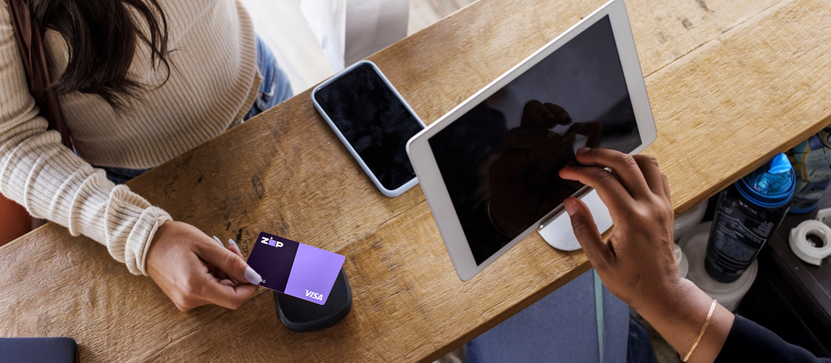 Customer tapping a Zip Visa card on a payment reader while a merchant rings up the sale on a tablet with buy now, pay later (123)