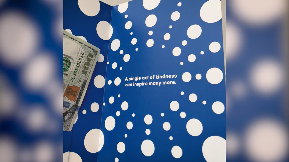 Klick Kindness Kit envelope with one hundred dollar bill and text that reads "a single act of kindness can inspire many more."