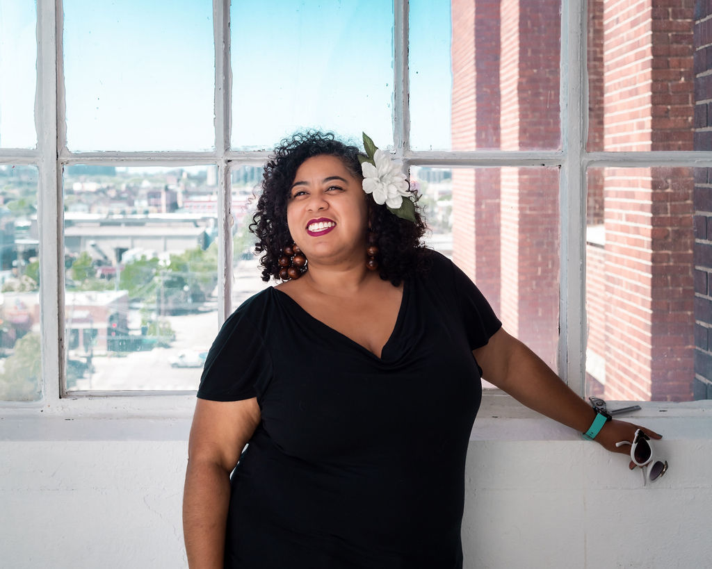 Author Kara smiling as she stands in front of a big window