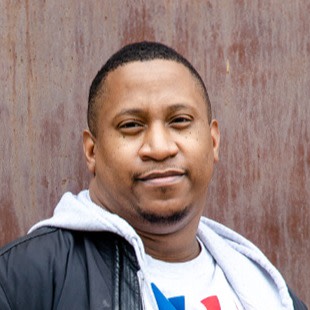 Photo of Jerome Hardaway posing in front of an industrial-looking wall.