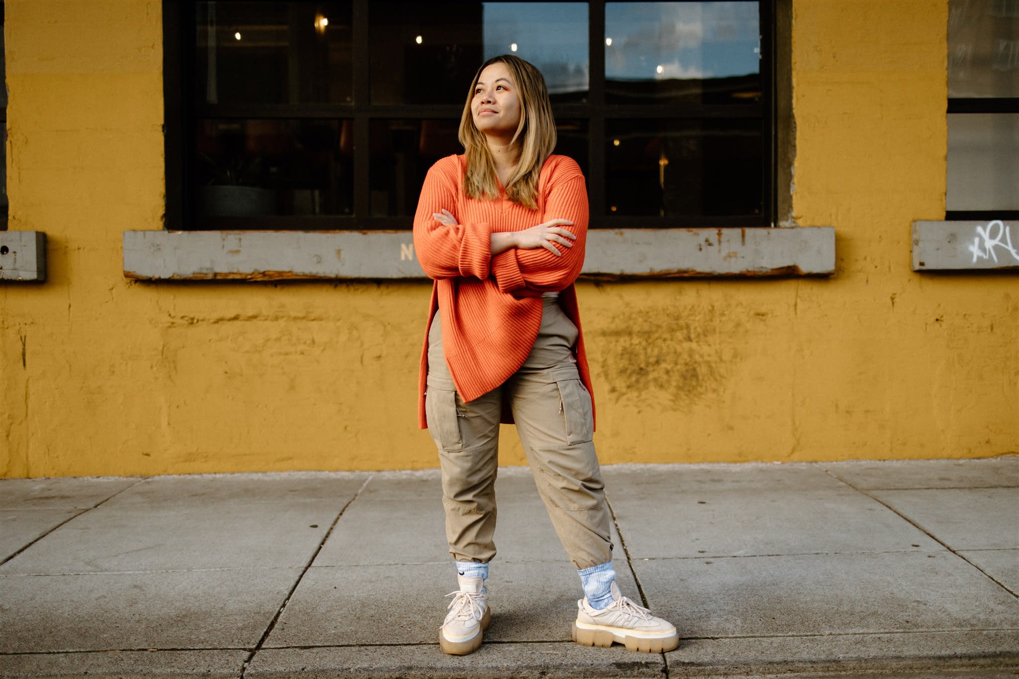 Author Tatiana gazing up as she stands in front of a yellow wall outside