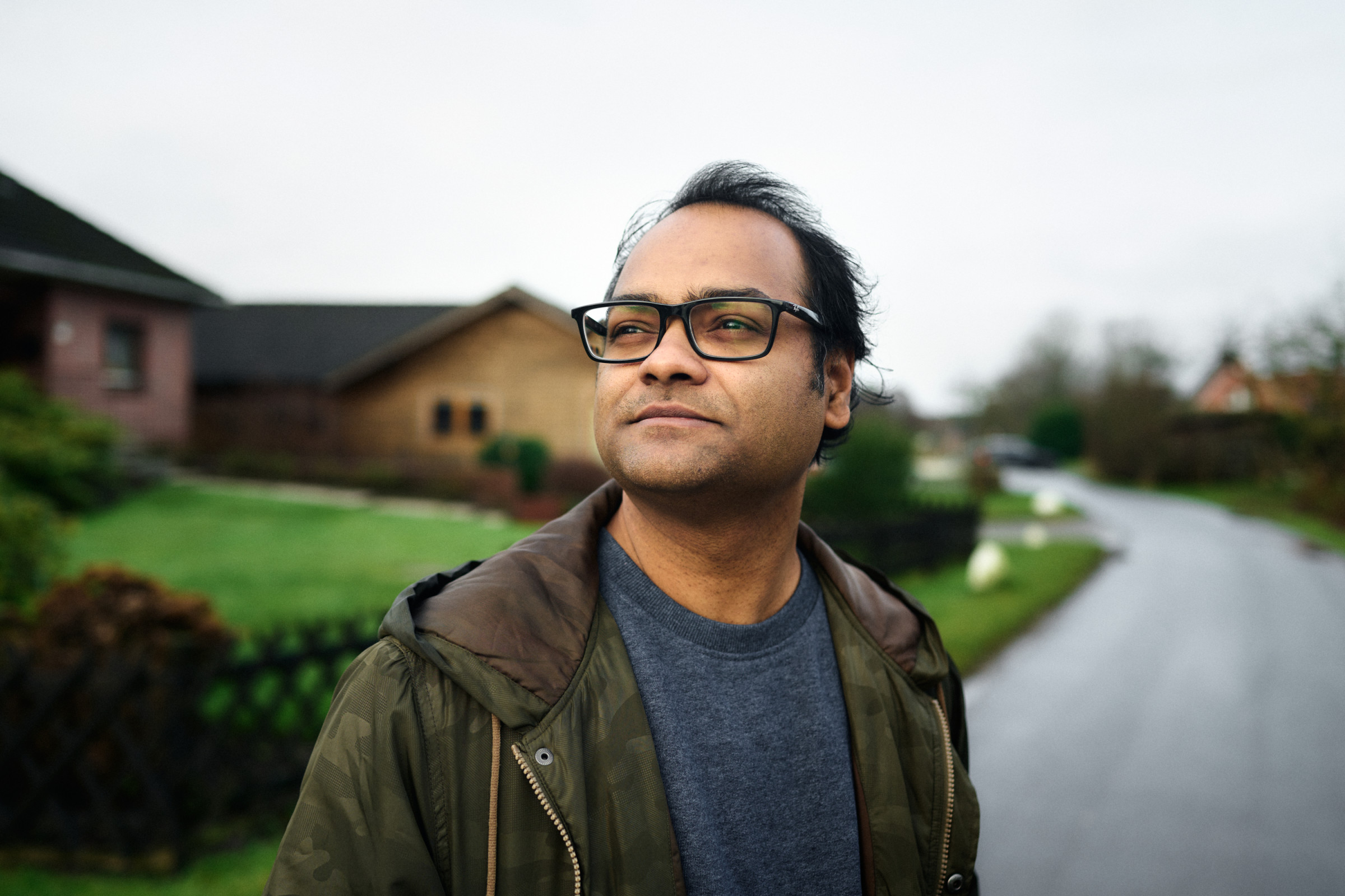 Author Santosh gazing to the side as he stands on the street in a neighborhood