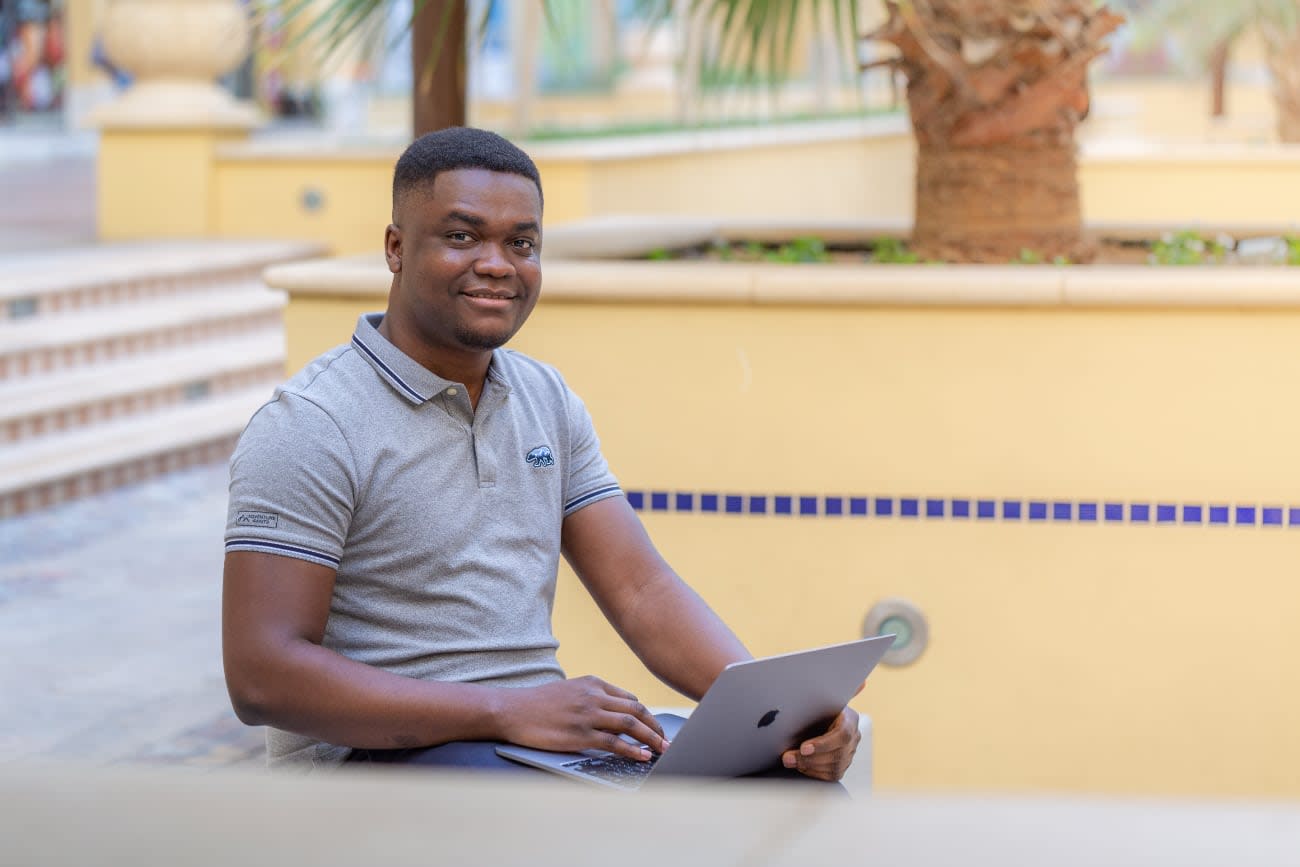Photo of Segun Adebayo coding outdors on his laptop.