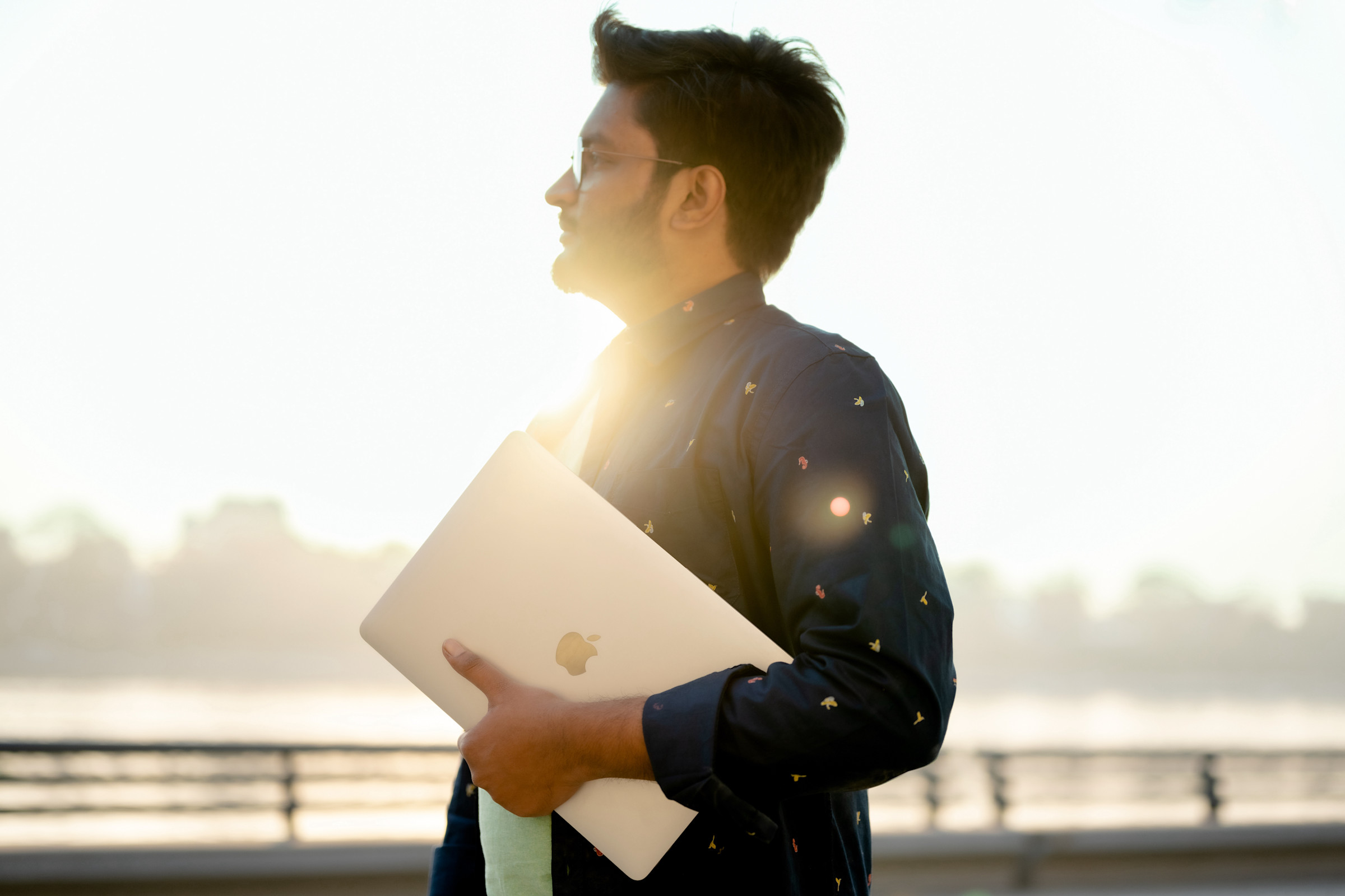 Author Karthik standing with his laptop in front of a sunny marina