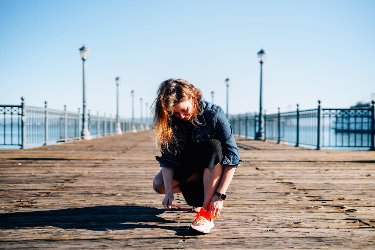 Photo of Kathy Korevec at a pier tying shoelaces.