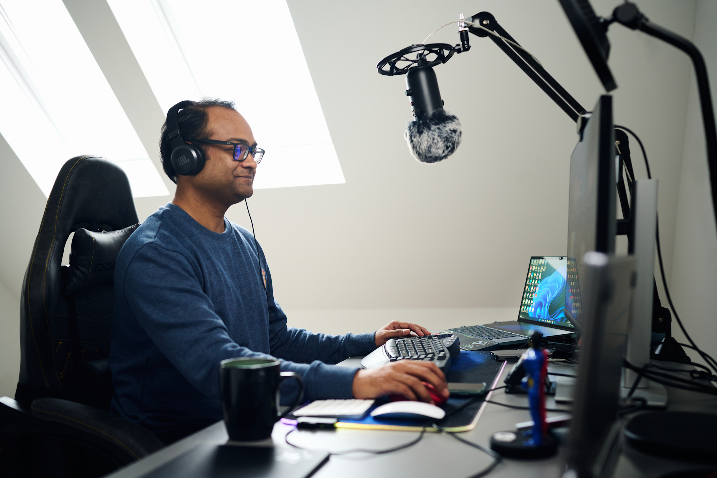 Santosh working at a desk and computer while wearing headphones.