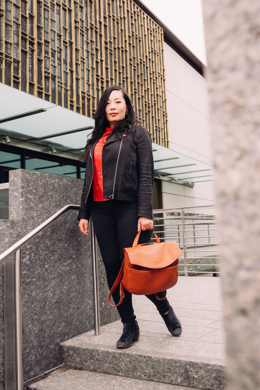 Photo of Shirley Wu outdoors, staning on a stairway holding her bag.