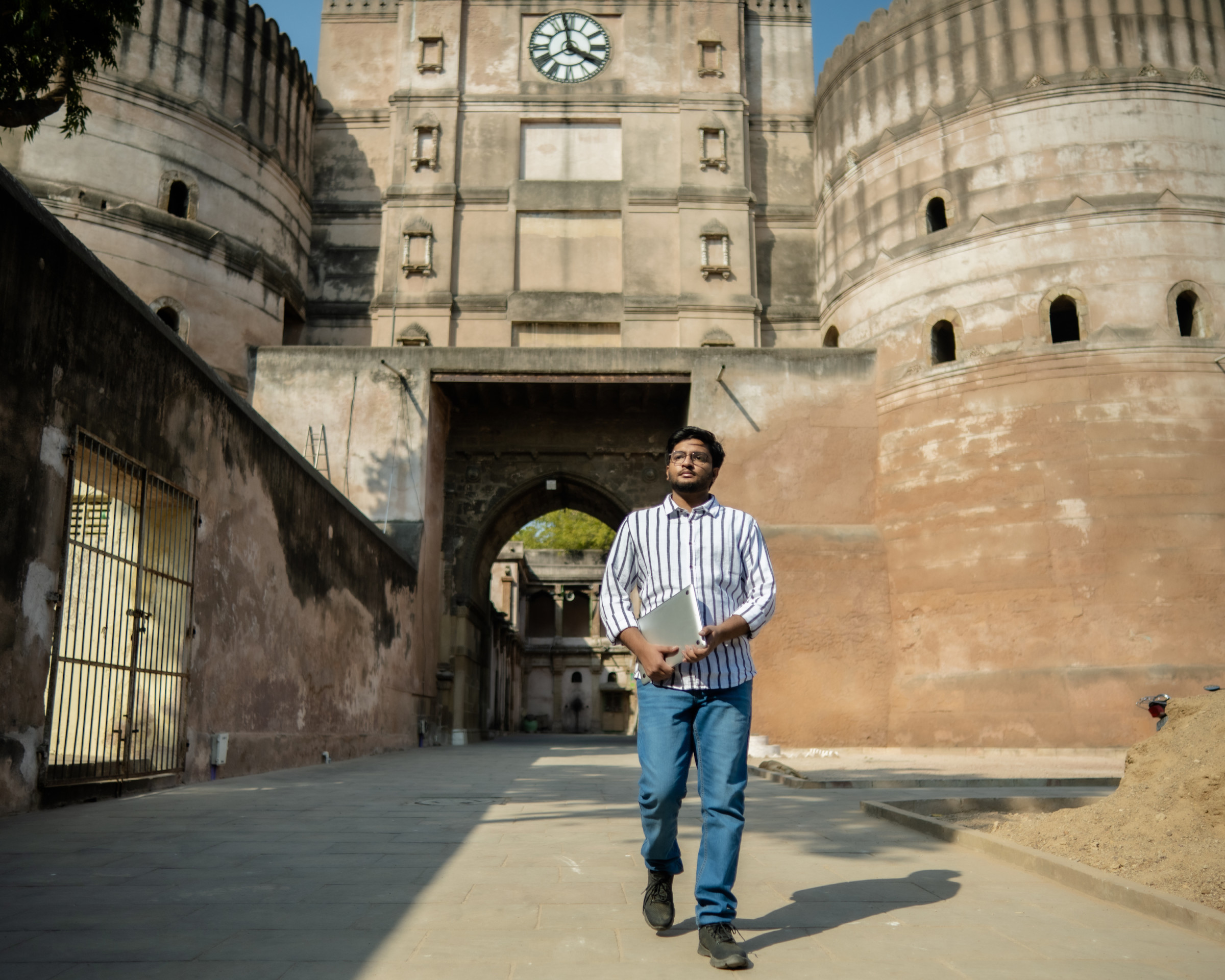 Author Karthik walking with his laptop in front of an old building