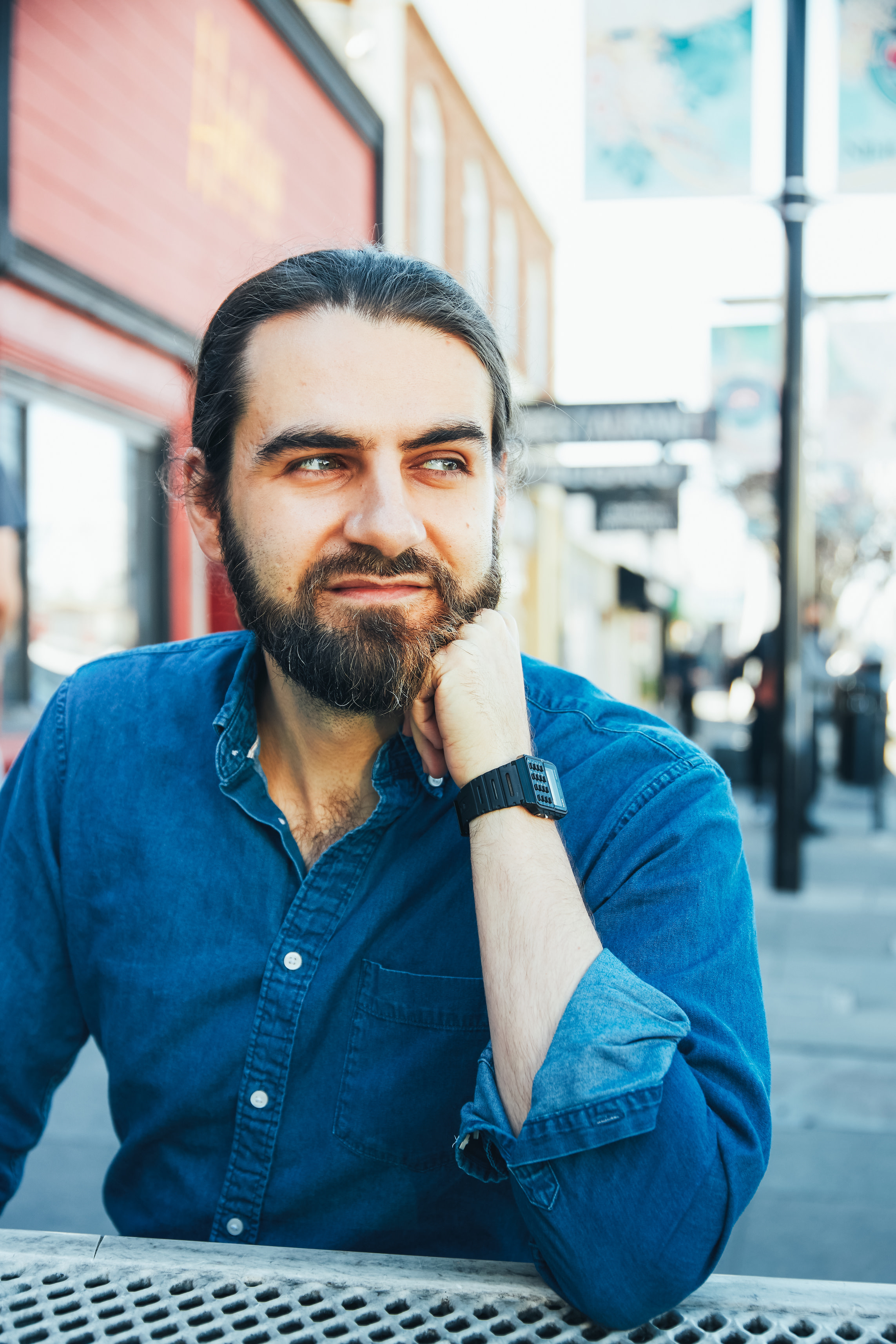 Author Mahmoud sitting at an outdoor table, gazing to the side