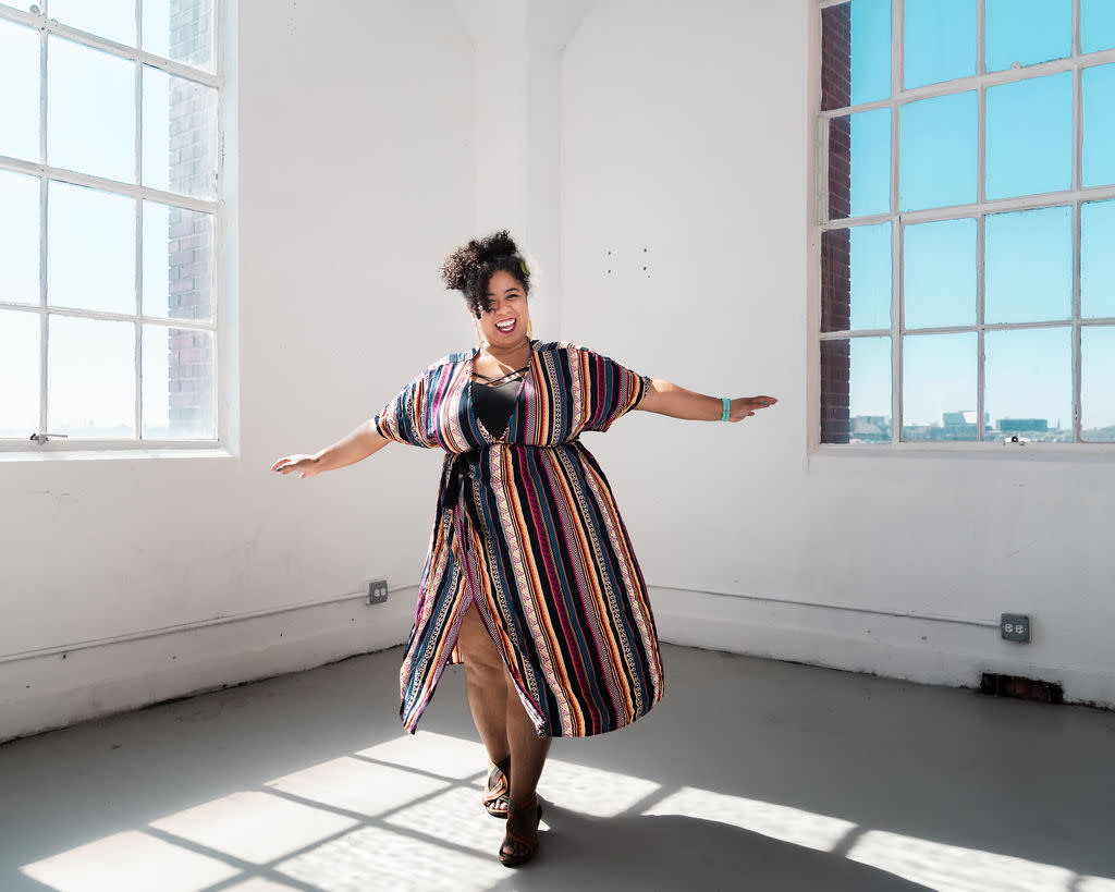 Author Kara smiling and twirling in a sunny loft