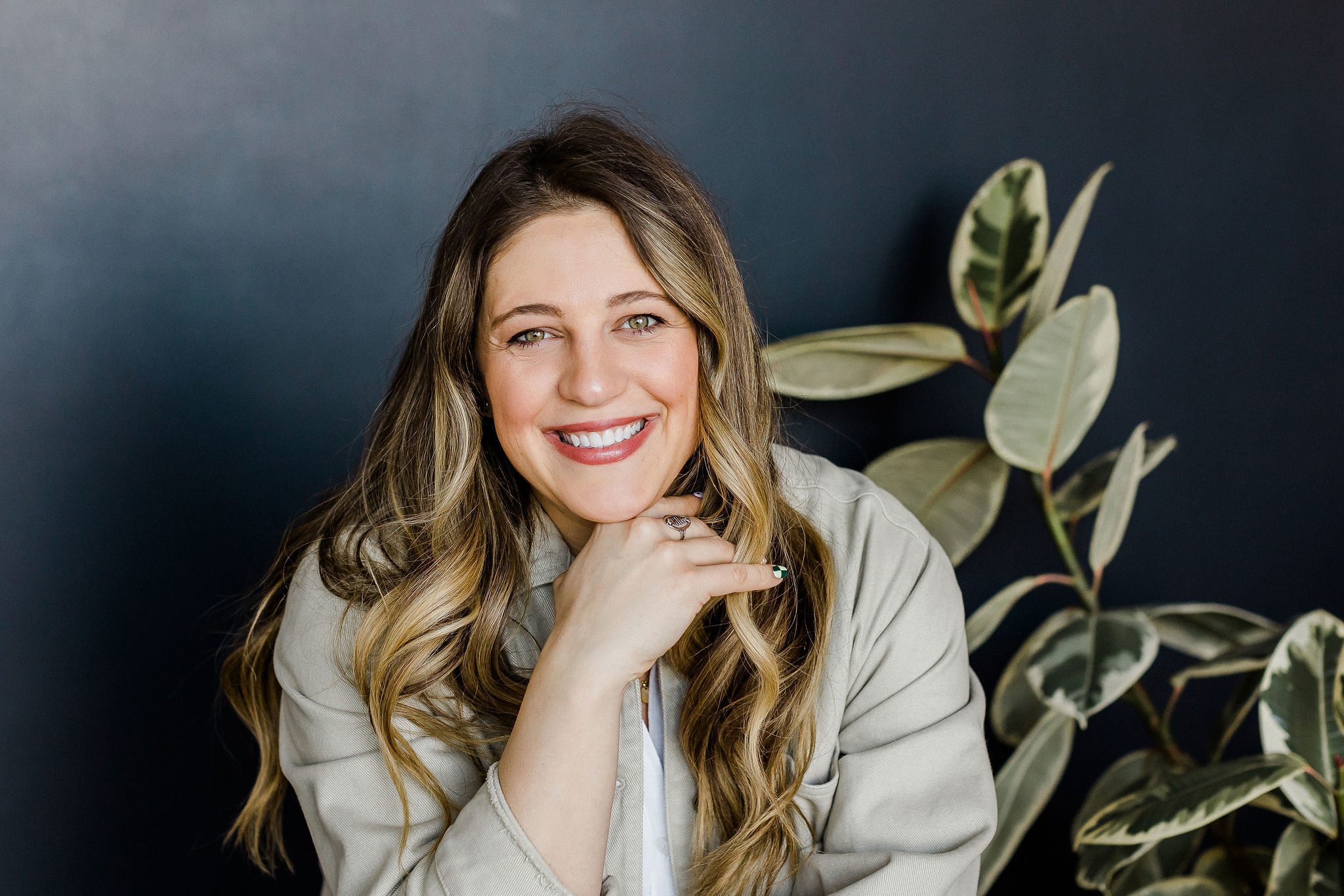 Close-up of author Rose sitting next to a plant against a charcoal-colored backdrop