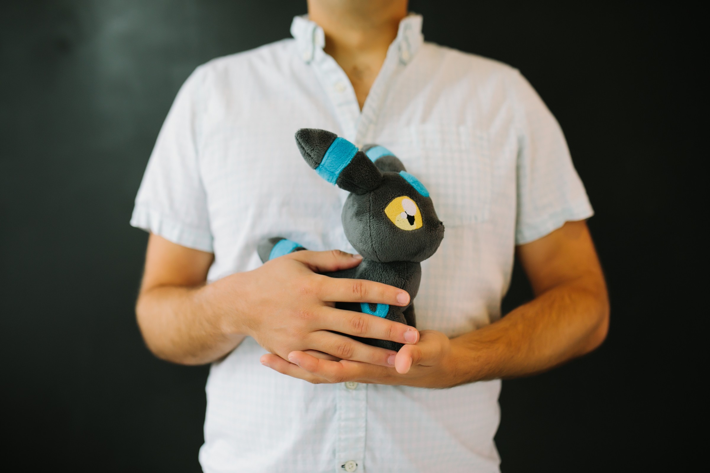 Author Anthony holding a stuffed plush toy of Umbreon from the Pokemon series