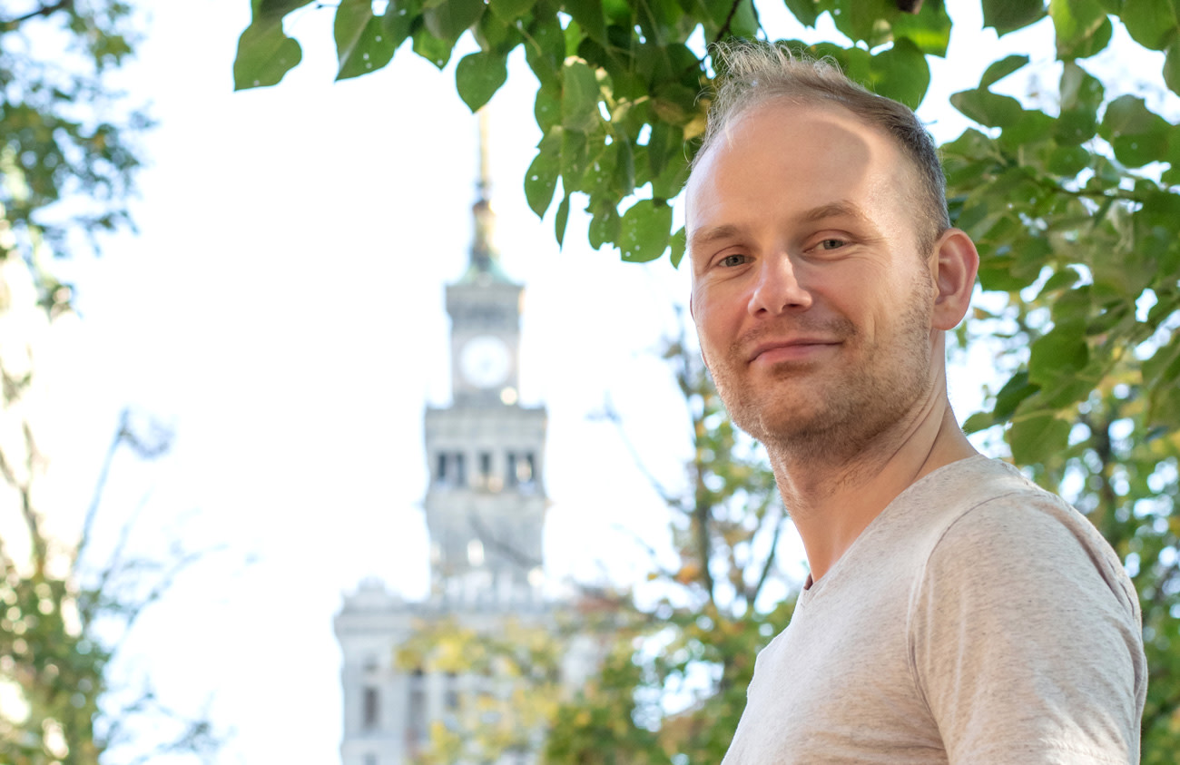 Photo of Michał standing outdoors in Warsaw.