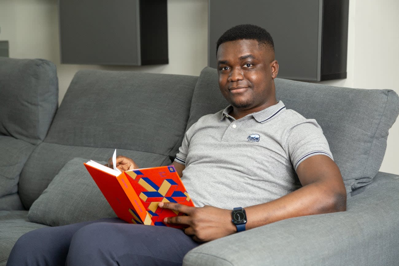 Photo of Segun Adebayo reading a book Working in Public: The Making and Maintenance of Open Source Software by Nadia Eghbal.