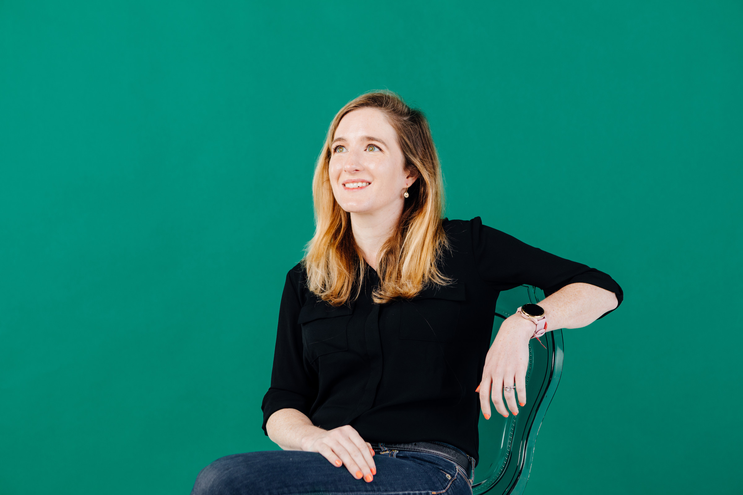 Author Keeley sitting in a chair and gazing up against a kelly green backdrop