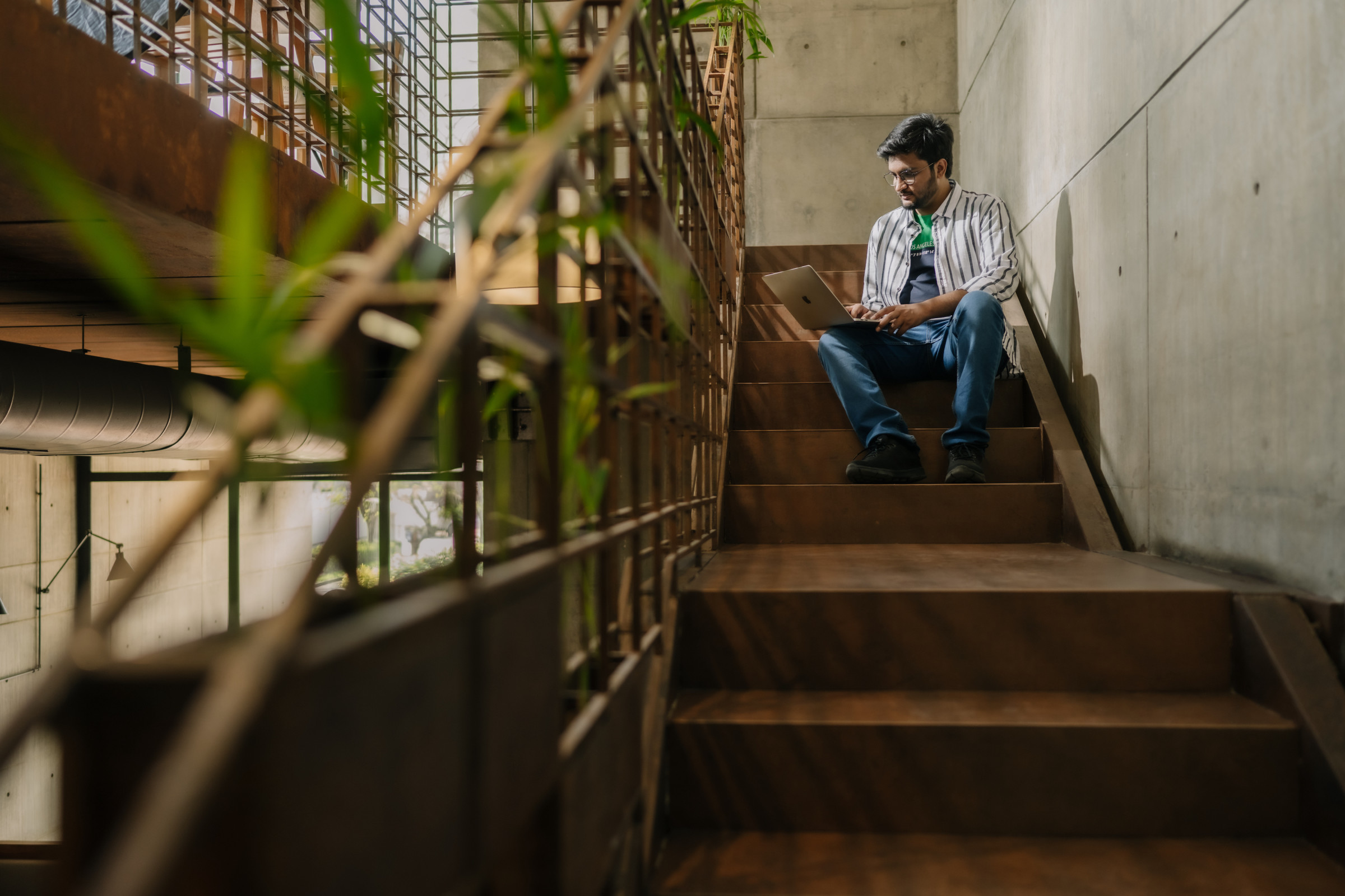 Author Karthik sitting on an urban staircase working on his computer