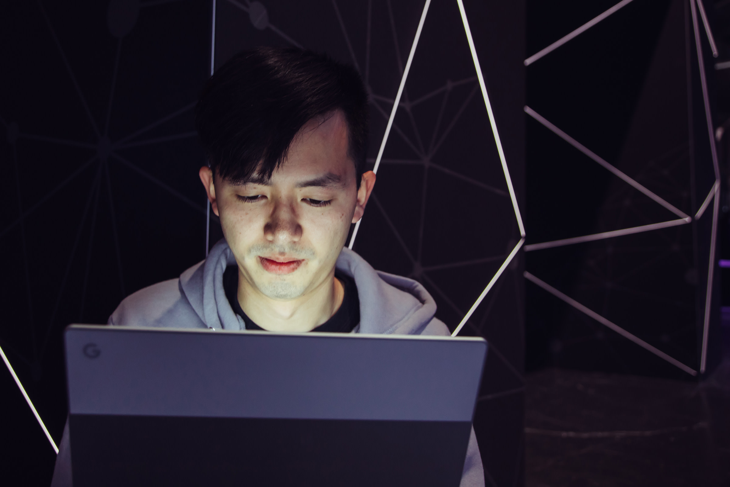 Photo of Henry Zhu working, face illuminated by their laptop screen.