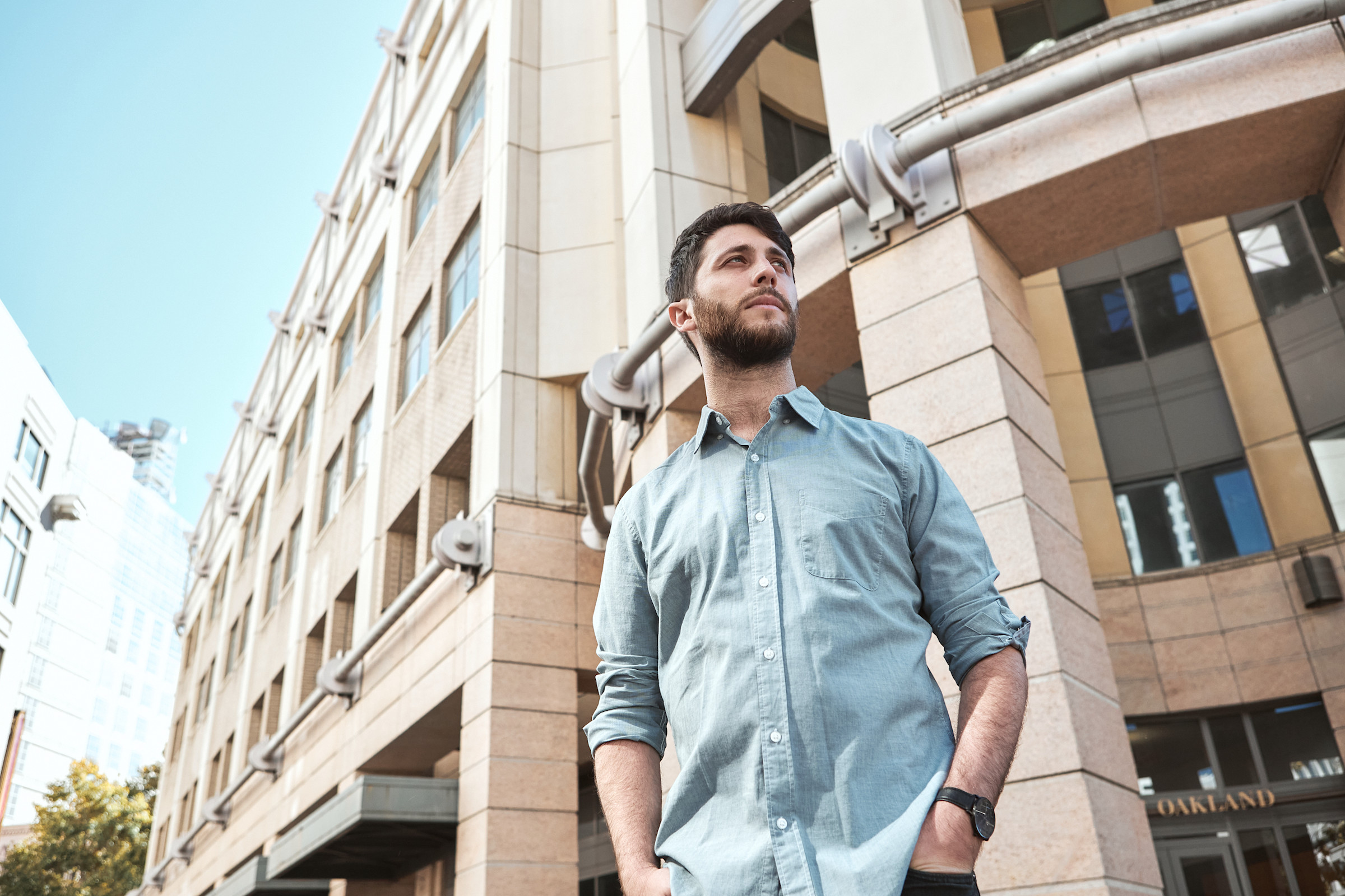 Author Avi standing in front of an office building against a blue sky