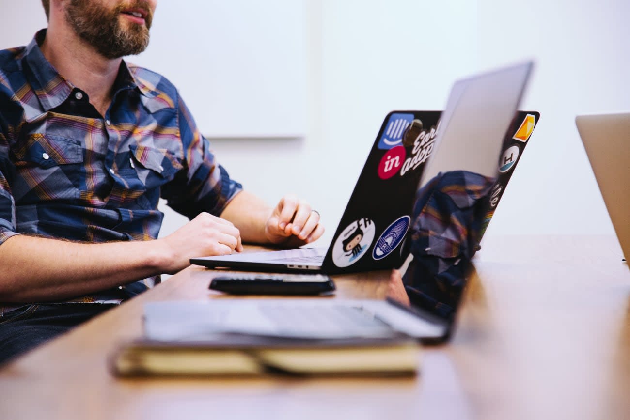 Photo of a male developer next to his laptop full of stickers.