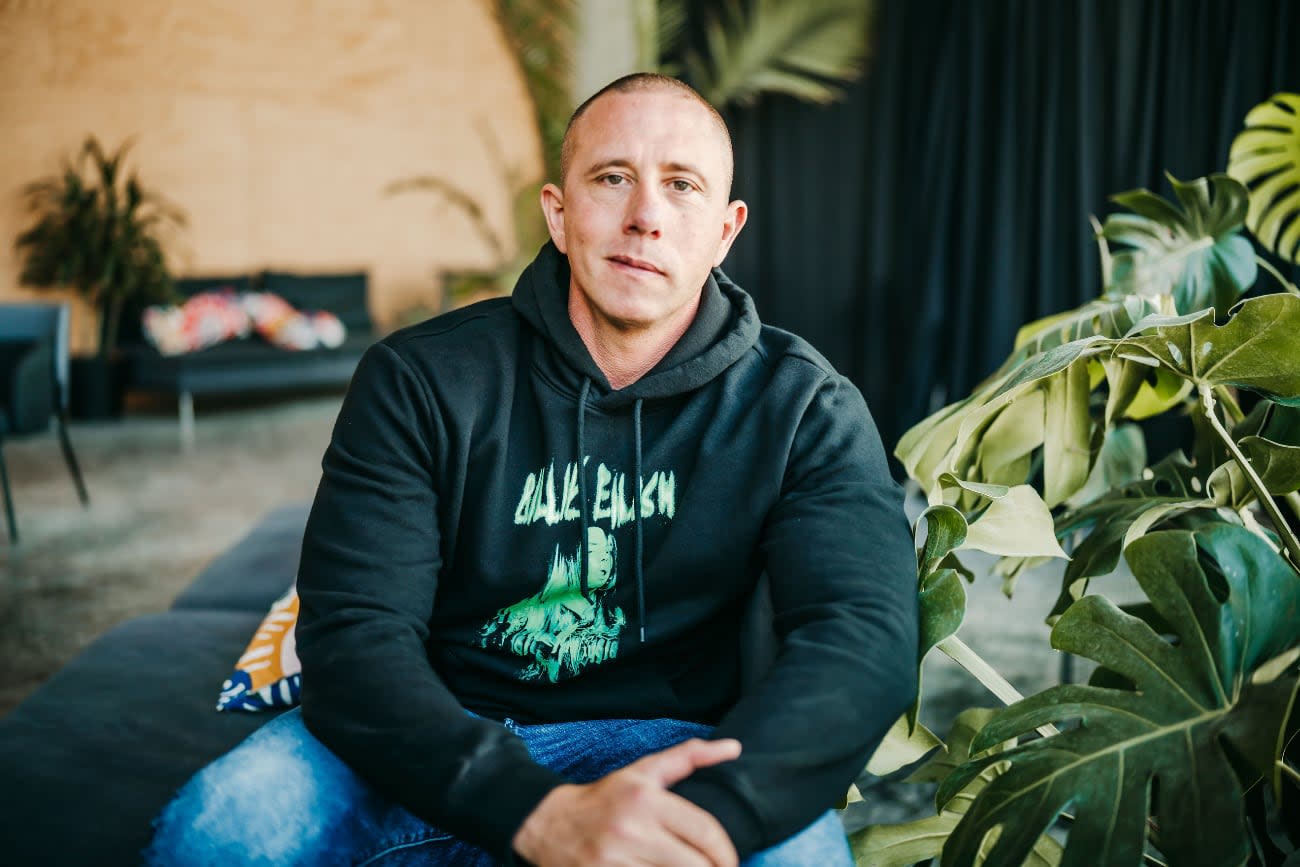 Photo of Nader Dabit sitting indoors in a lobby next to a plant.