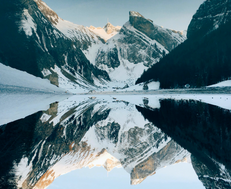 Snow capped mountains with perfect reflection in water below.