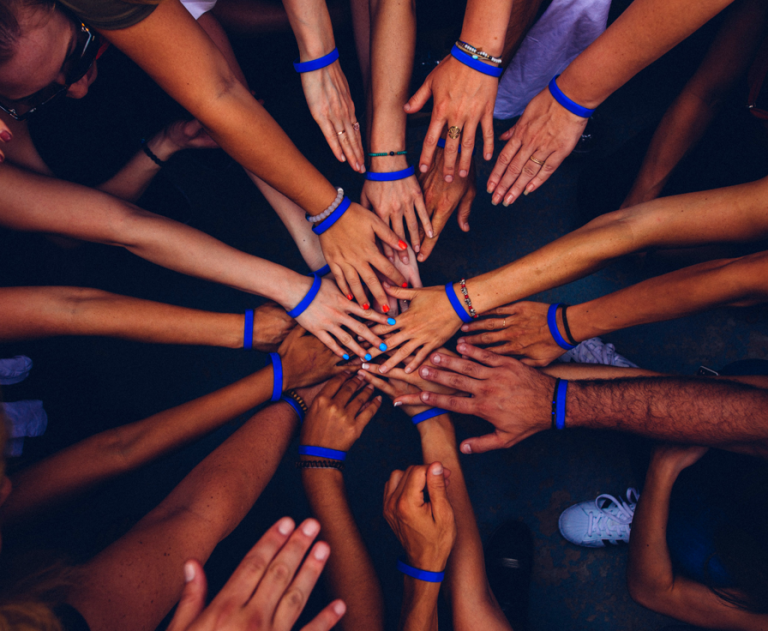 Many hands reaching in together as a sign of working together.