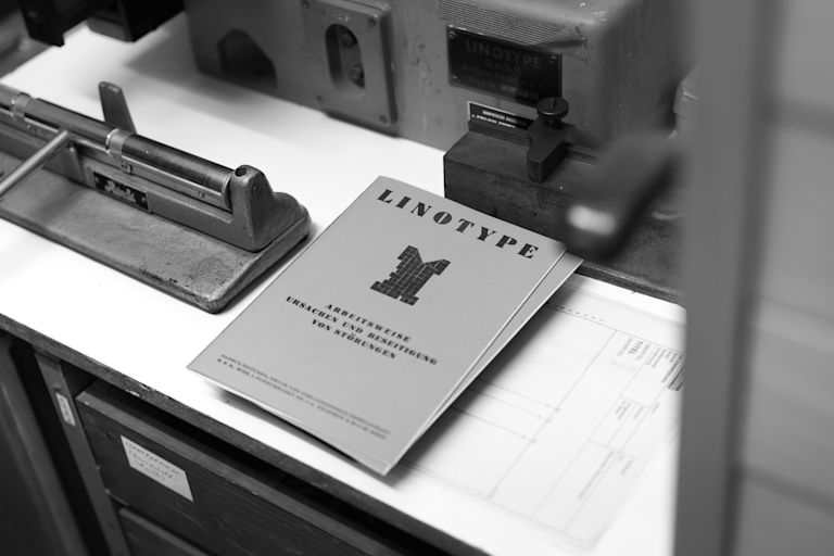 A Linotype Machine and Manual are set and ready on a desk in Germany, representing WYSIWYG history. by 4motions Werbeagentur