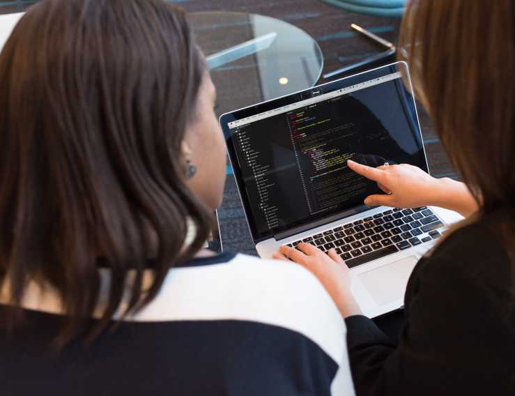 Two women discussing a piece of code