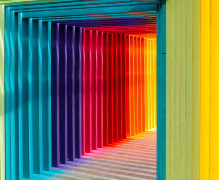 A brightly coloured corridor lined with rainbow-colored wooden arches.