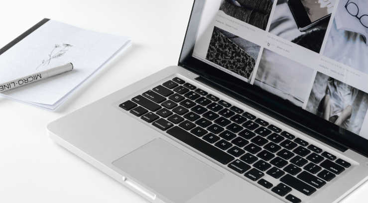 A laptop and notebook on a table, representing the single scree and side-by-side WYSIWYG HTML editing by Mel Poole