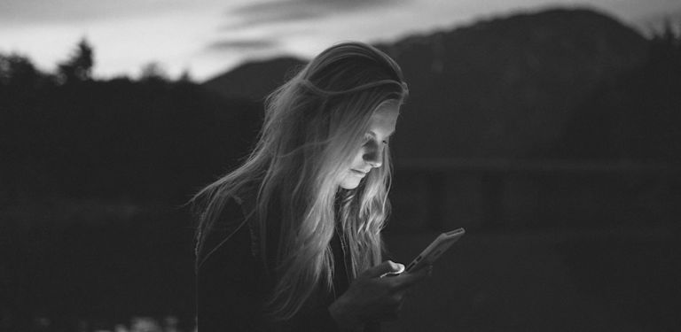 A woman peers into a glowing smartphone, contemplating the tech industry. by Becca Tapert