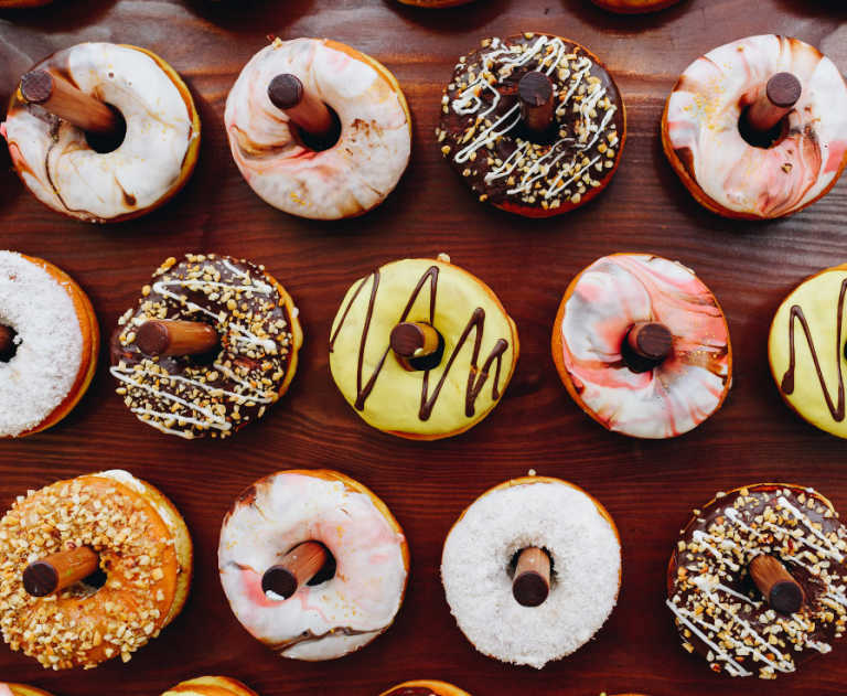 An assortment of decorated donuts are displayed on a wooden donut board.