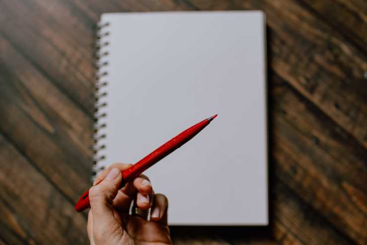 A person holding a red pen about to do some writing.  
