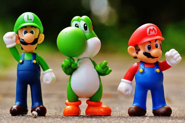 Super Mario, Luigi, and Yoshi figurines standing together on a hard surface.