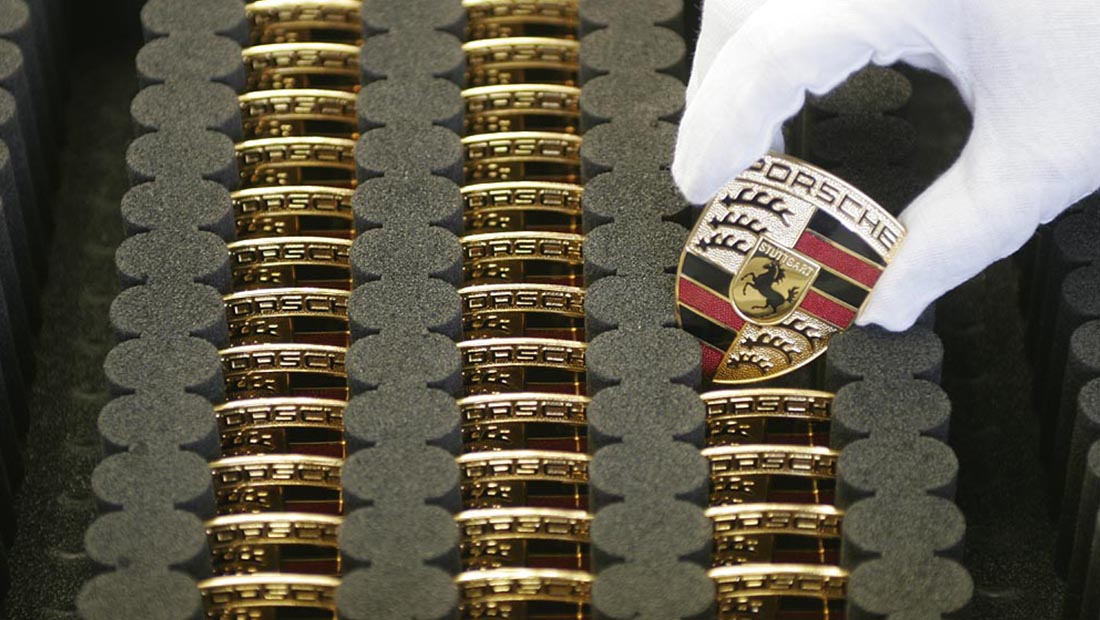 White-gloved hand removing a Porsche badge from a case