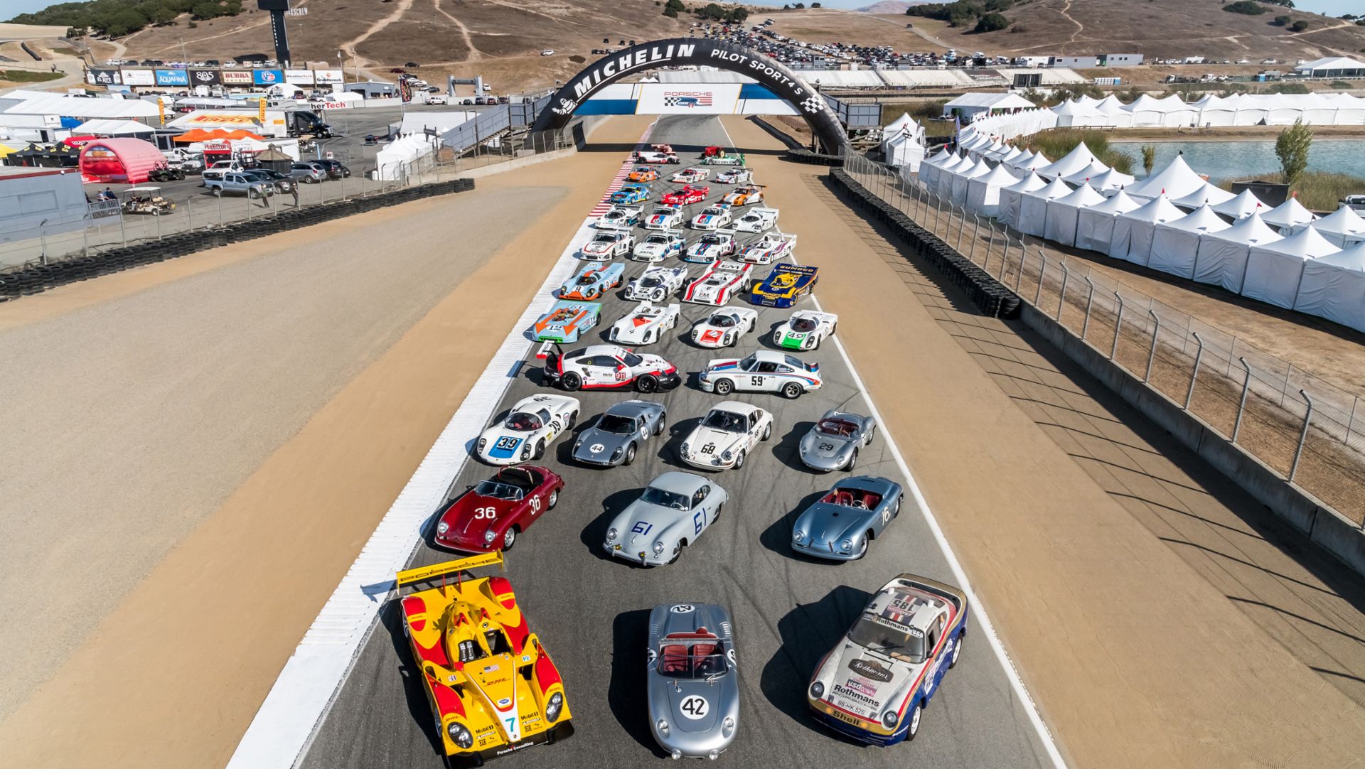 36 historic Porsche racecars parked along a racetrack