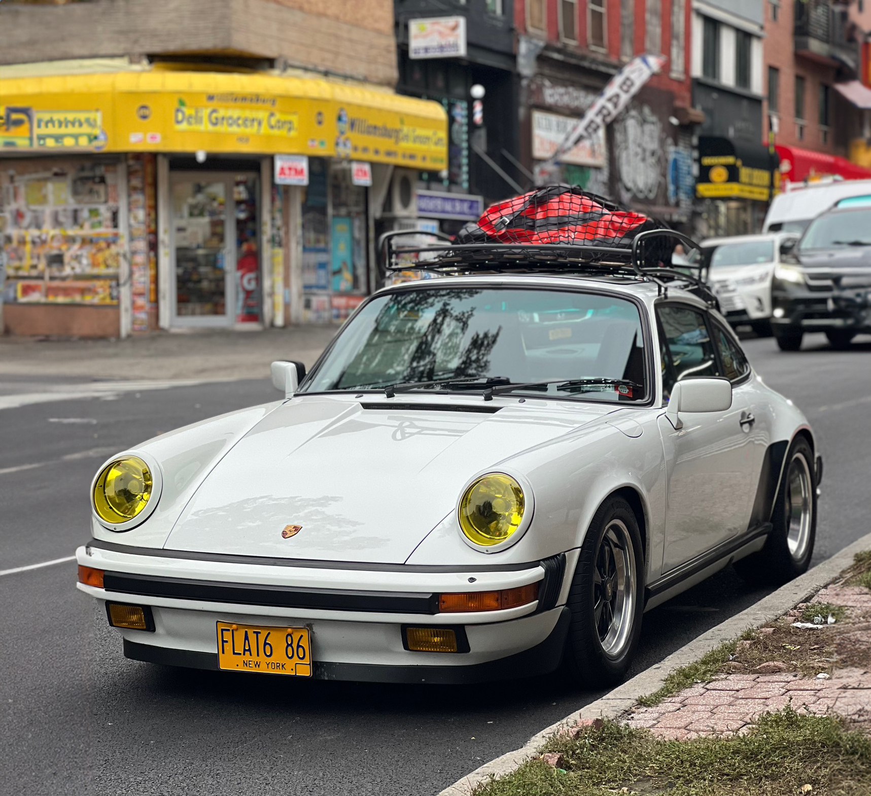 White Porsche 911 (type G-series) on road with roof rack