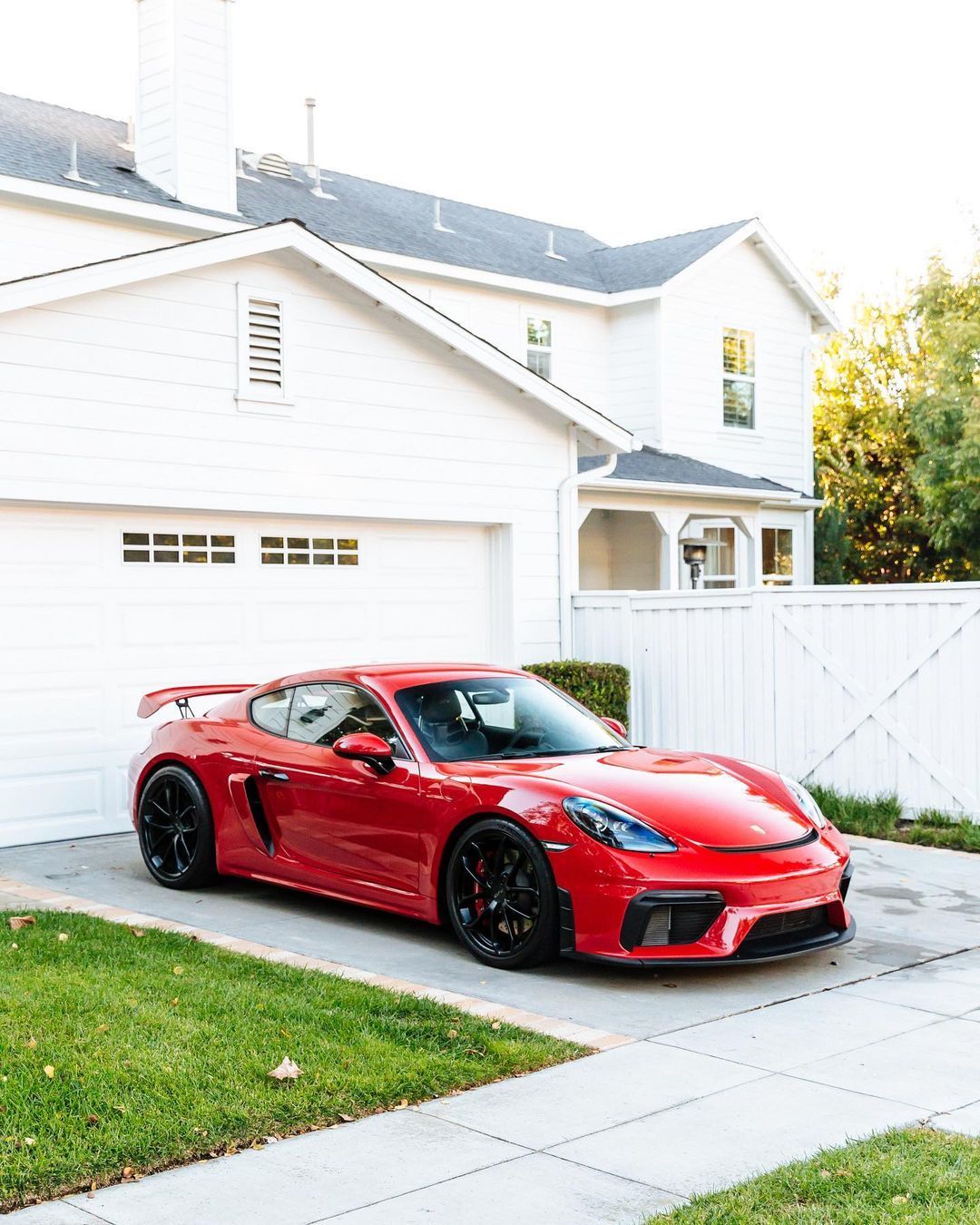 Red Porsche GT4 parked in driveway of suburban home